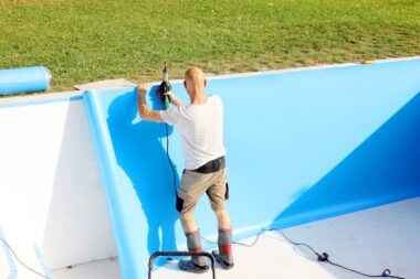 A worker welds plastic cover for water pool. Water pool cover replacement. Plastic Welding Machine. Swimming pool care concept.