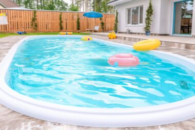 Fiberglass white pool with blue clear water and floating inflatable rings. Relax in the backyard of a house or private mini-hotel.